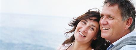 femme-et-homme-riant-avec-la-mer-en-arriere-plan